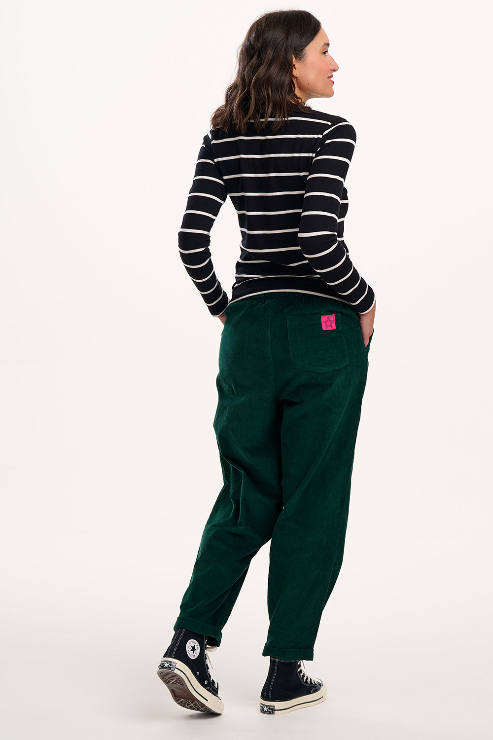 Person wearing a black and white striped shirt and green trousers on a white background