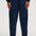 A person wearing dark navy corduroy jogger pants with an elastic waistband and cuffs, paired with white sneakers and a black top with patterned sleeves, shown against a plain light background.
