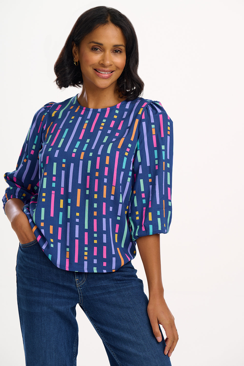 A model wearing a blue blouse with horizontal multicolor lines and 3/4 blouson sleeves.