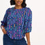 A model wearing a blue blouse with horizontal multicolor lines and 3/4 blouson sleeves.