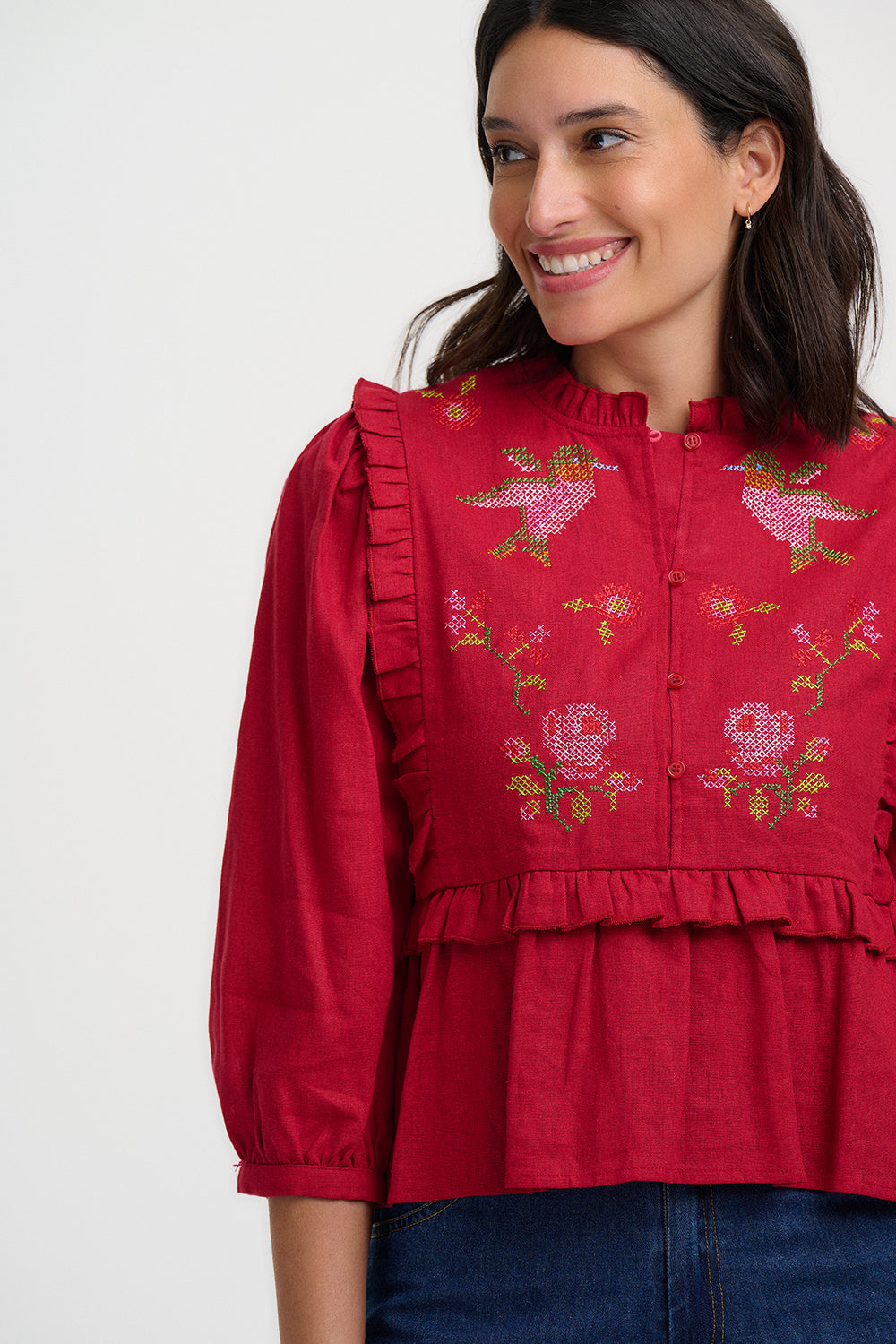 Woman wearing a red embroidered blouse with floral patterns on a white background