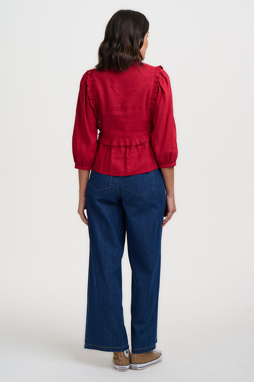 Person wearing a red top and blue jeans on a white background