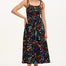 A model wearing a sleeveless, midi-length jersey dress with a multicolored jungle print on a black background, featuring tie shoulder straps.