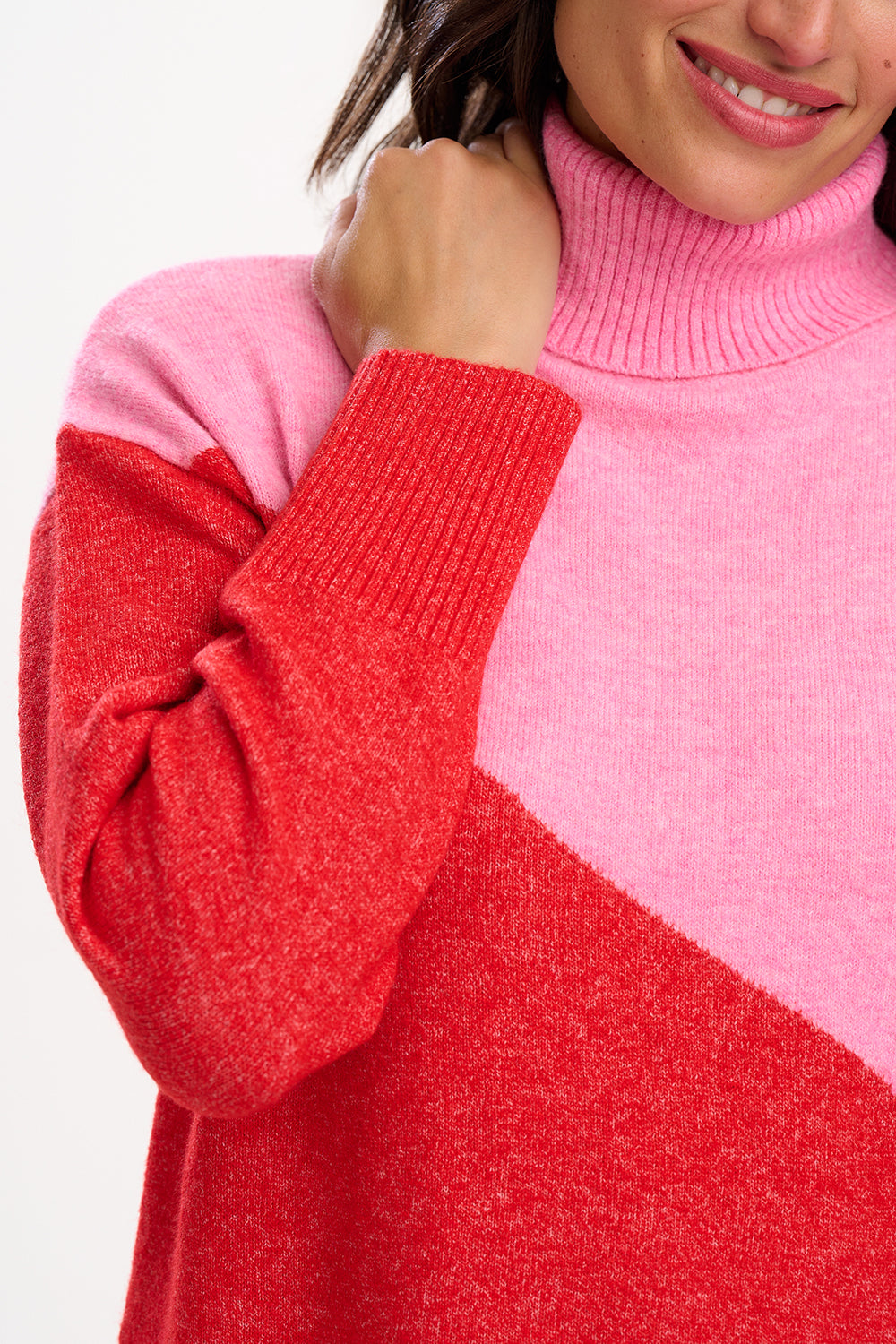 Close-up of a person wearing a pink and red color-blocked sweater.