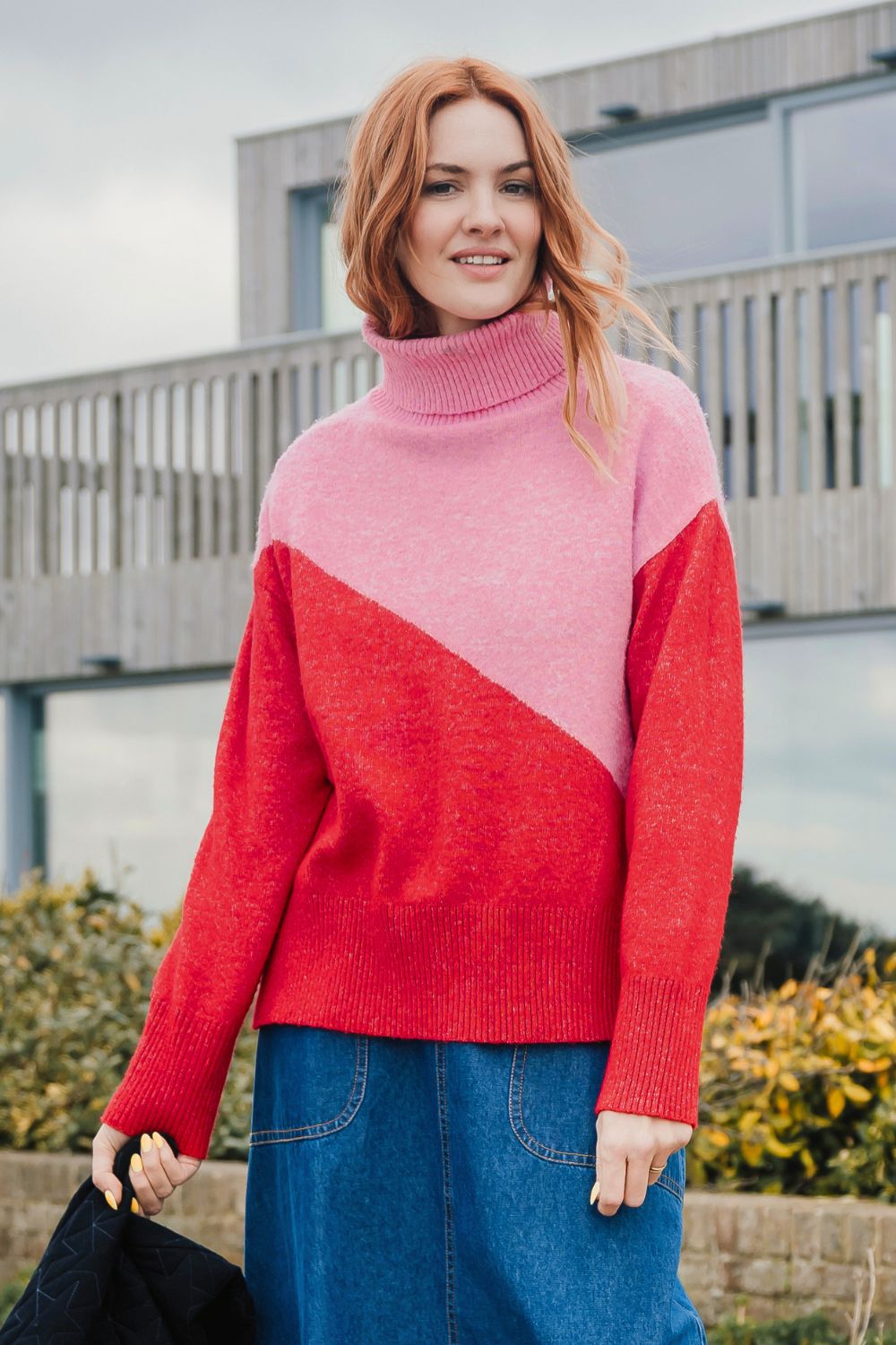 Woman wearing a pink and red sweater standing outdoors.