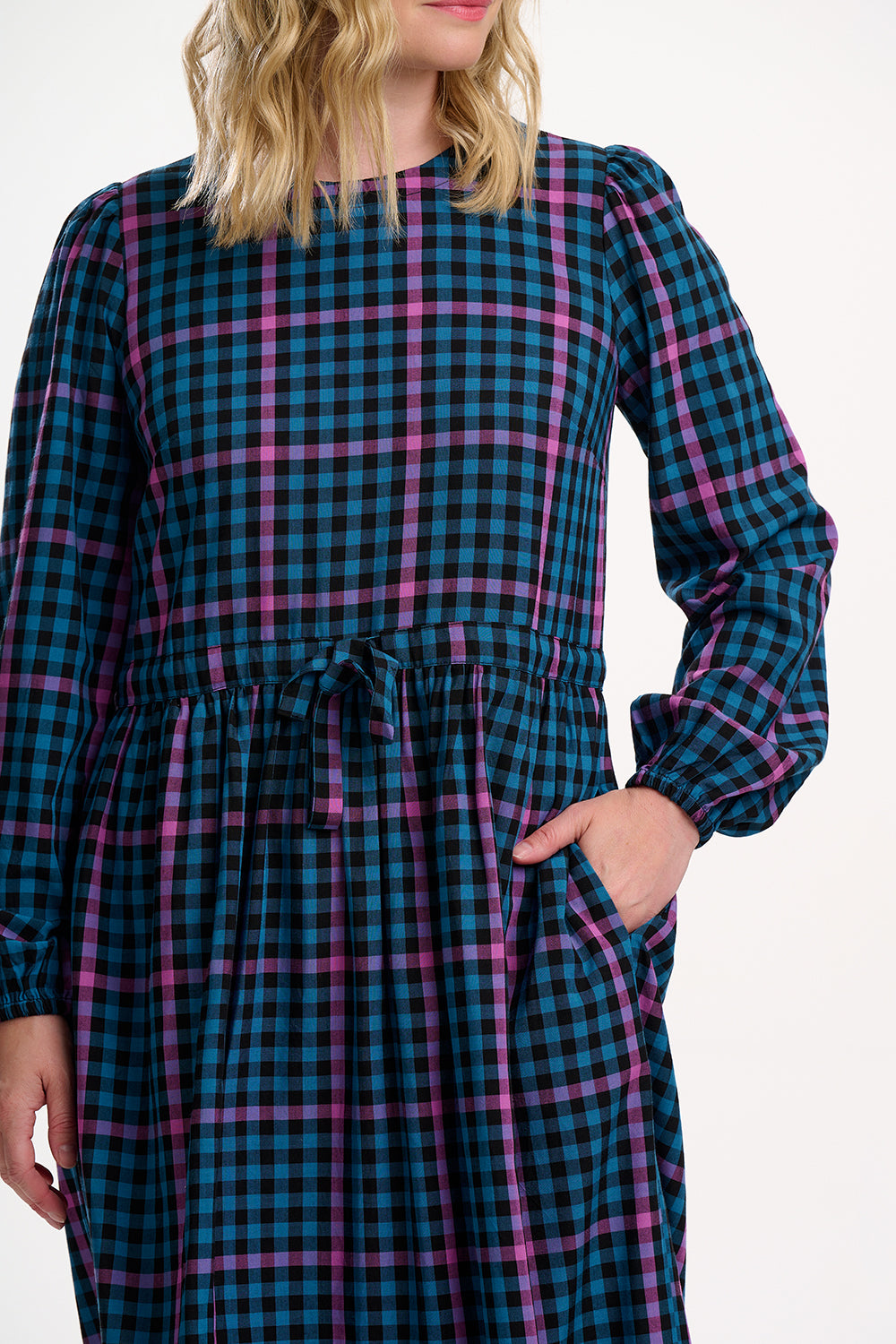 Sugarhill Brighton model wearing a blue and pink plaid dress with long sleeves on a white background
