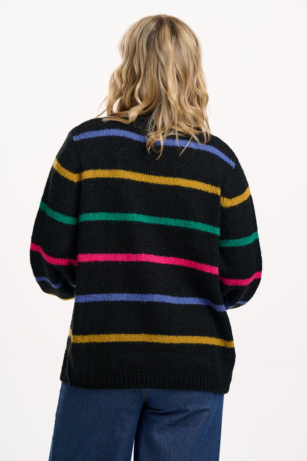 Person wearing a black sweater with colorful horizontal stripes on a white background