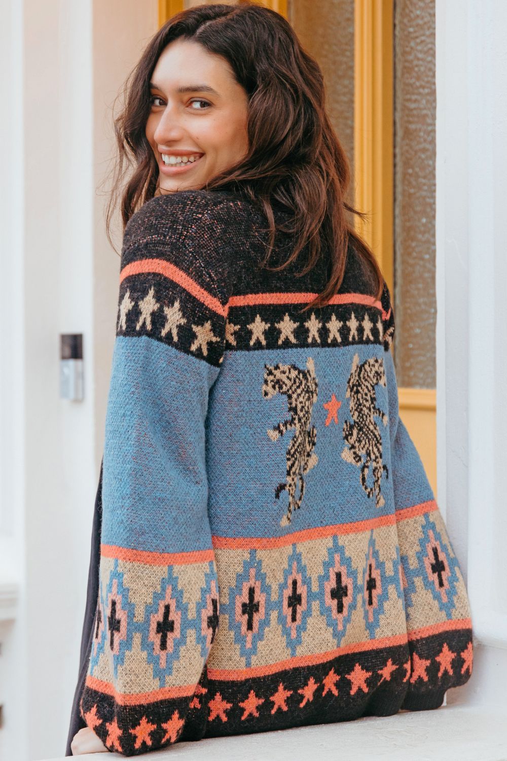 Woman wearing a patterned sweater with a blue and black design.