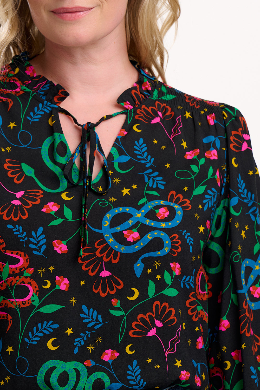 Close-up of a person wearing a black blouse with colorful abstract patterns.