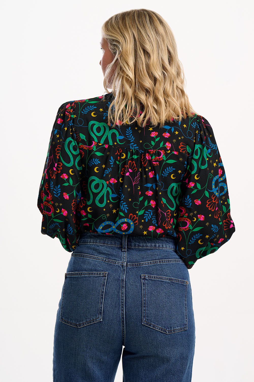 Person wearing a colorful patterned jacket and blue jeans on a white background