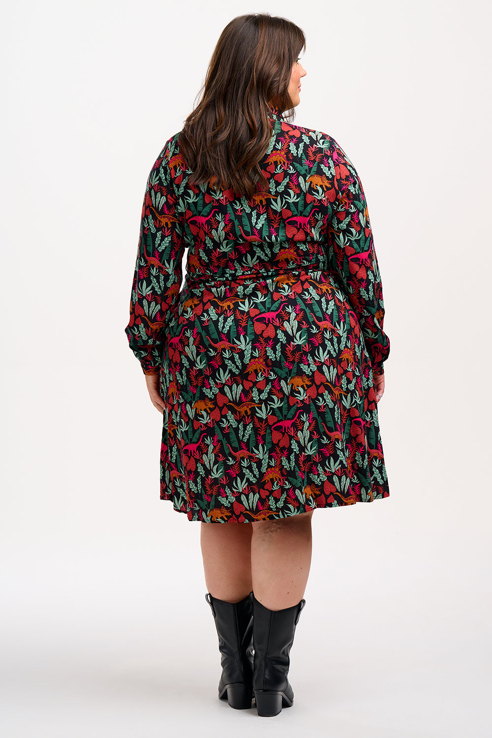 A woman wearing a black, floral shirt dress with a tie waist belt and relaxed collar.