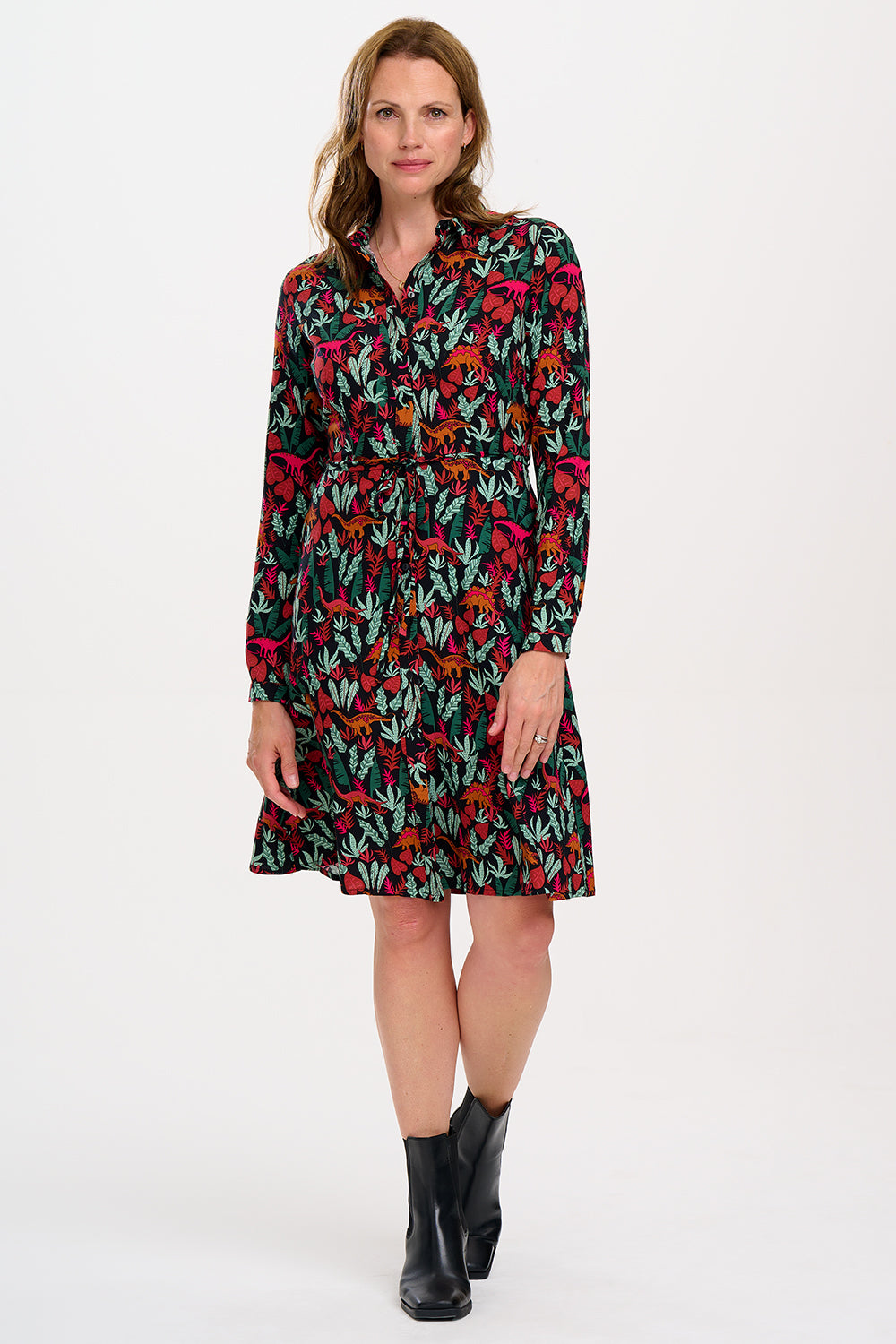A woman wearing a black, floral shirt dress with a tie waist belt and relaxed collar.