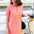 Woman in a pink dress standing next to a yellow scooter on a street.