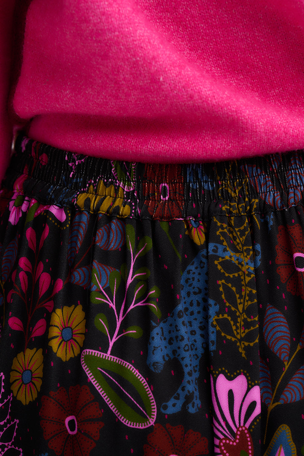 Close-up of a colorful patterned skirt with a bright pink top.