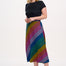 A woman standing and wearing a high-waisted, midi-length Zora skirt with a Rainbow Checkerboard design on a black base.