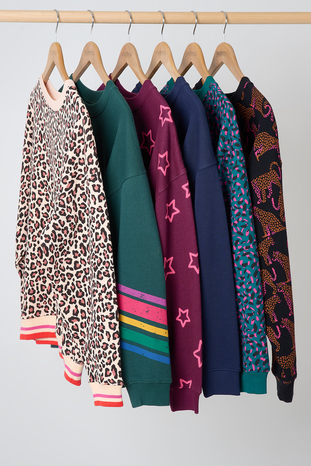 Colorful patterned sweaters hanging on a rack against a white background
