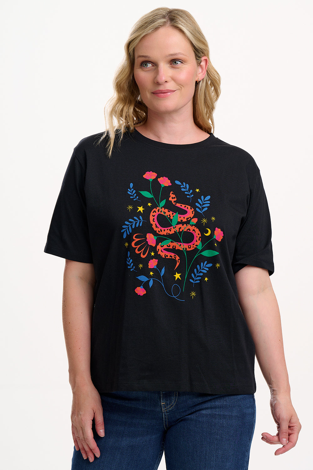 Woman wearing a black t-shirt with a colorful snake and floral design on a plain background