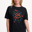 Woman wearing a black t-shirt with a colorful snake and floral design on a plain background