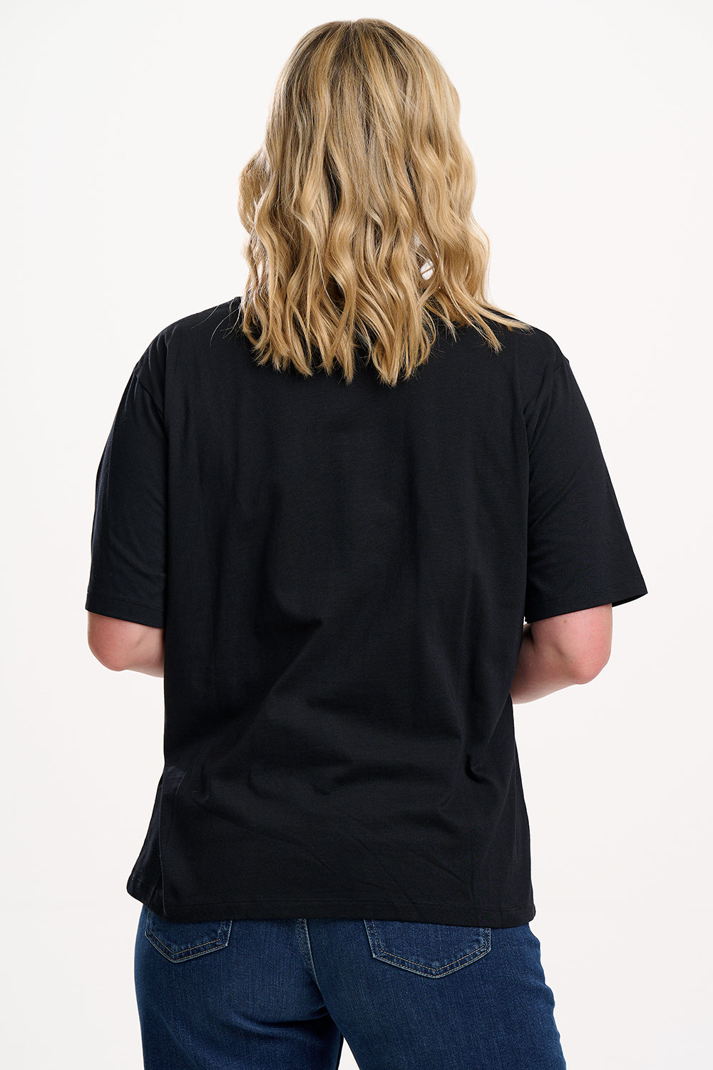 Person wearing a black t-shirt and blue jeans on a white background