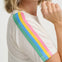 Woman wearing a white top with rainbow-colored straps on a plain background