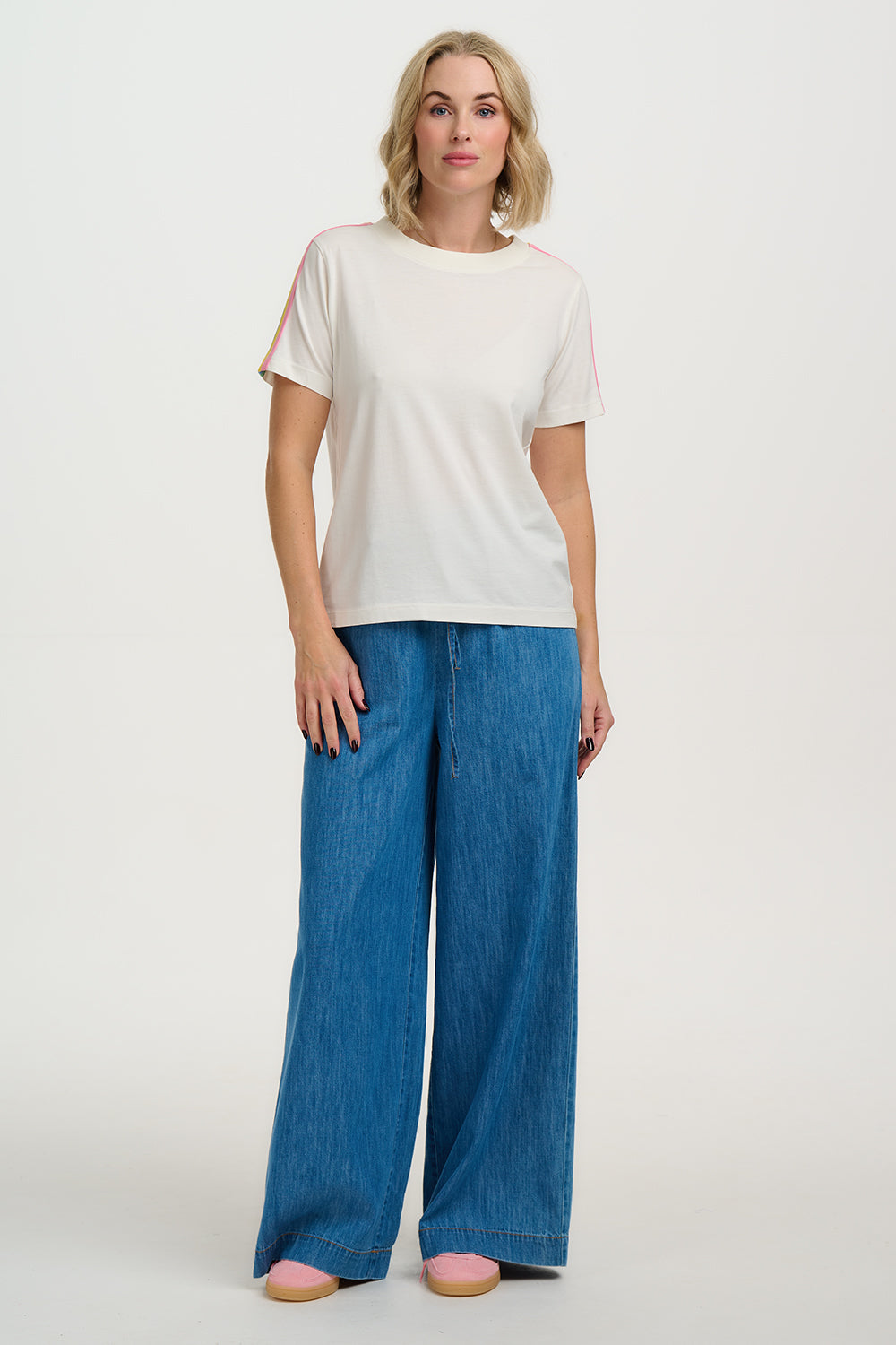 Woman wearing a white t-shirt and blue wide-leg pants on a white background