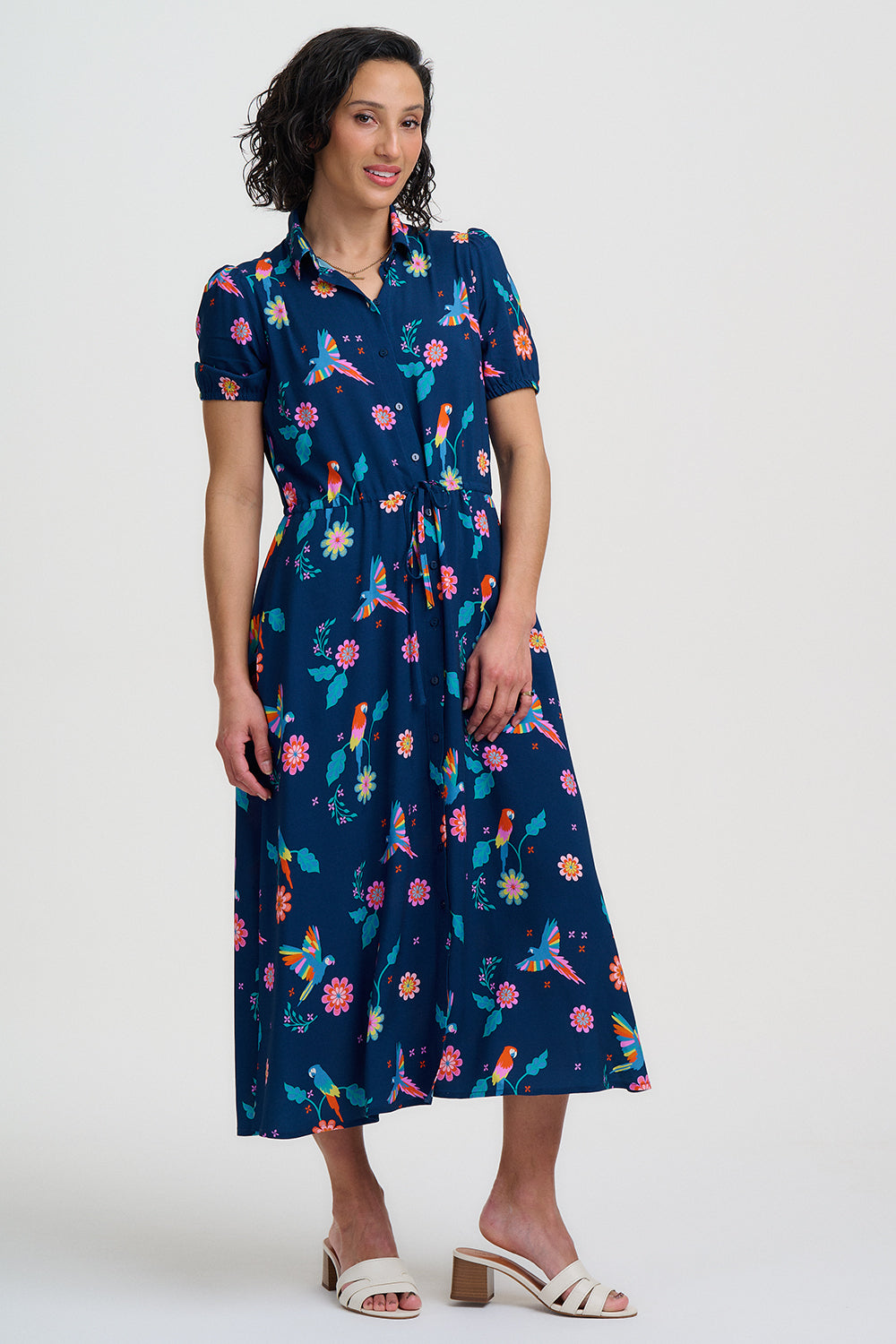 Navy blue dress with colorful floral and parrot pattern on a white background