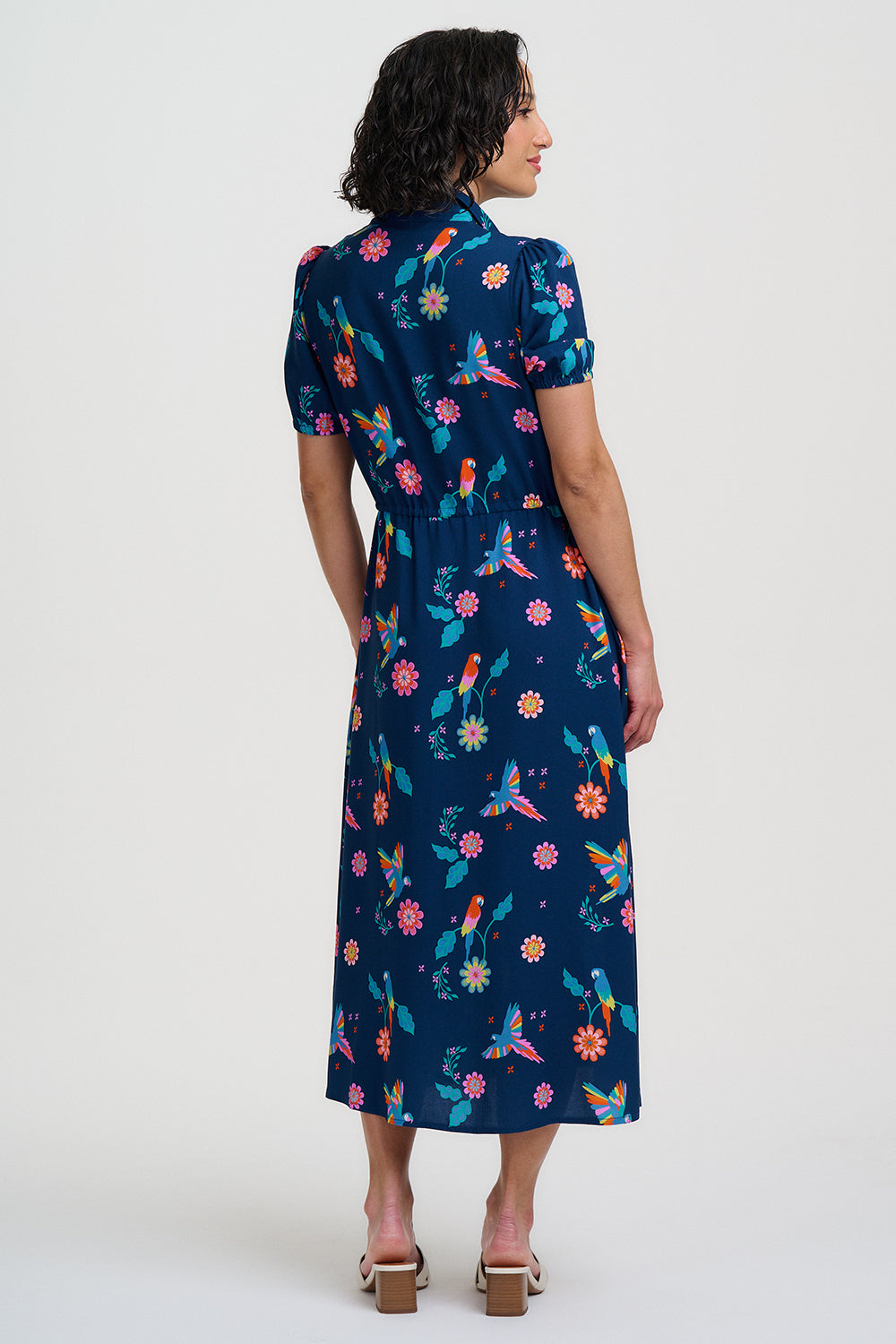 Navy blue dress with colorful floral and parrot pattern on a white background