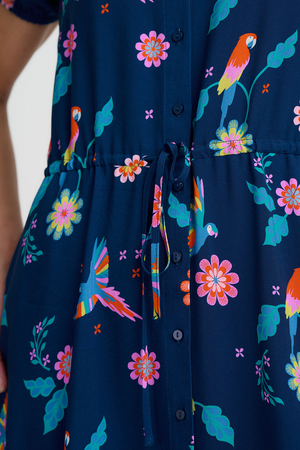 Navy blue dress with colorful floral and parrot pattern on a white background