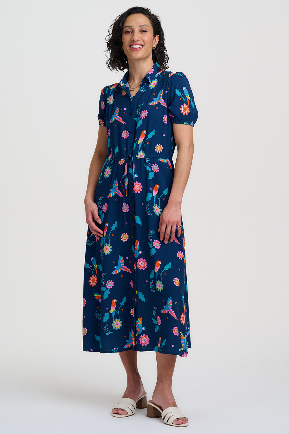 Navy blue dress with colorful floral and parrot pattern on a white background