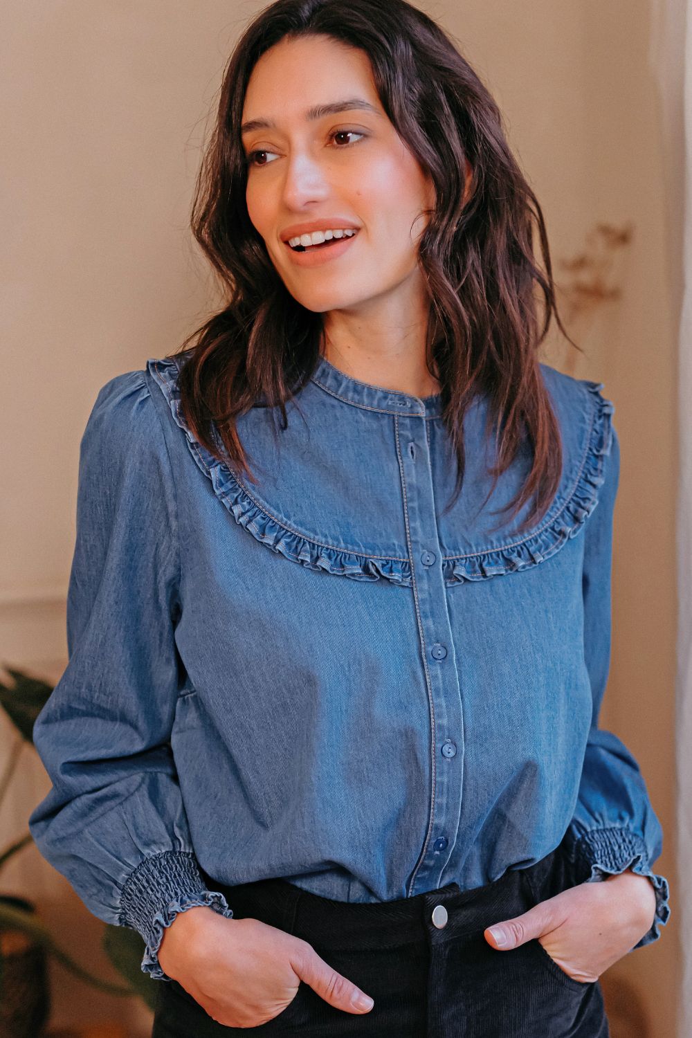 Sugarhill Brighton wearing a blue denim shirt with ruffled collar indoors