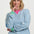 Woman wearing a blue and white striped sweater with green accents on a white background