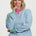 Woman wearing a blue and white striped sweater with green accents on a white background