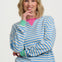 Woman wearing a blue and white striped sweater with green accents on a white background