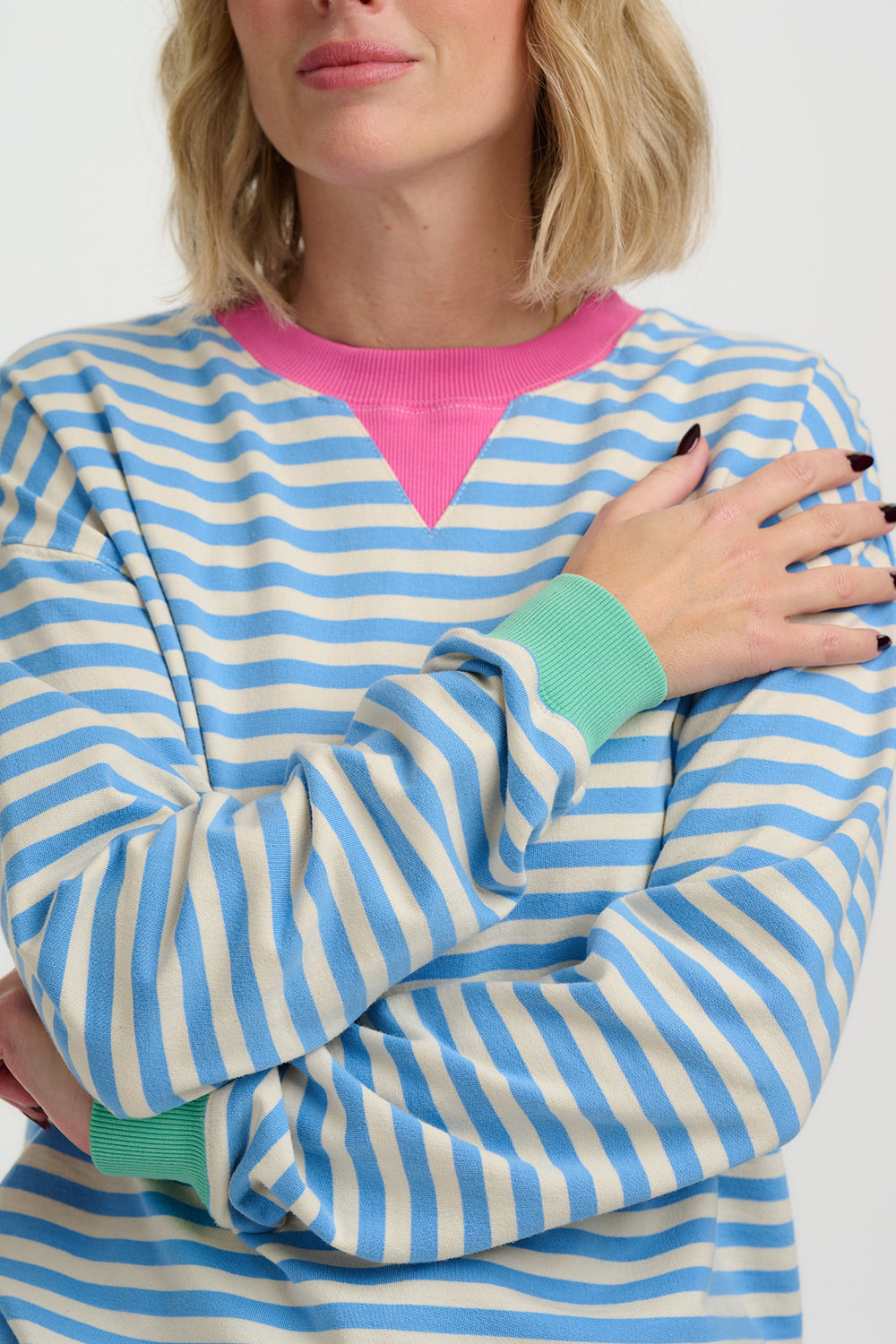 Person wearing a blue and white striped sweater over a pink shirt.
