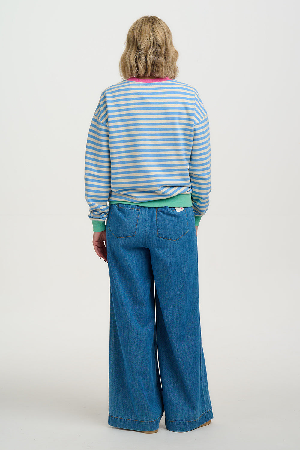Person wearing a striped shirt and blue jeans on a white background