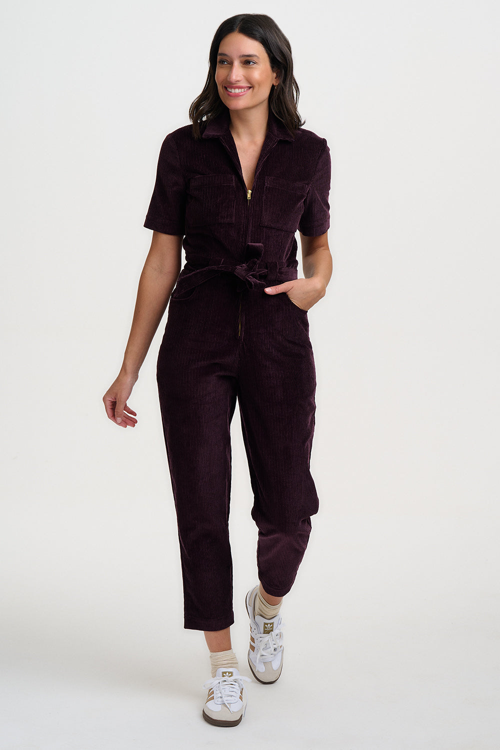 Woman wearing a dark brown jumpsuit on a white background