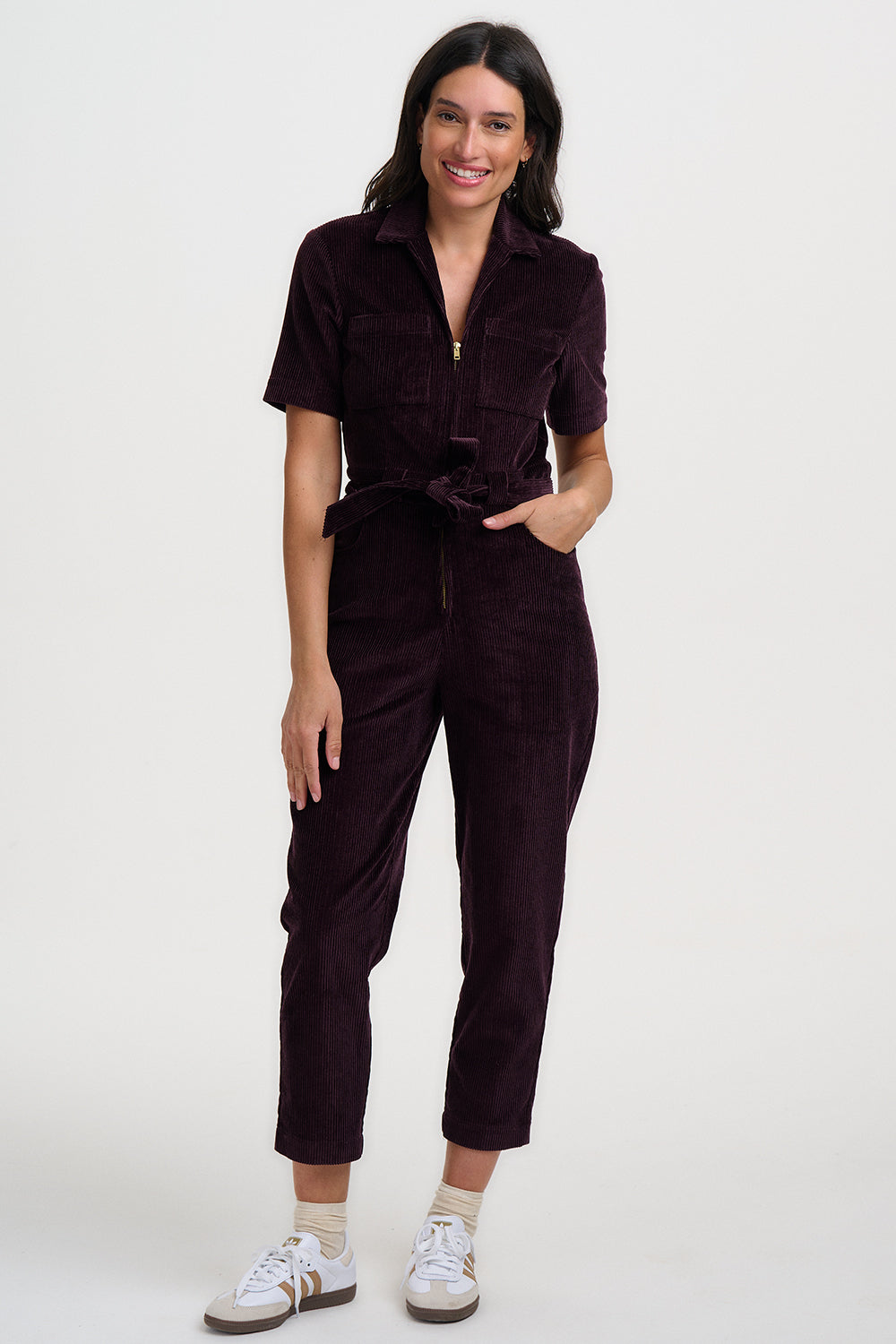 Woman wearing a dark brown jumpsuit on a white background