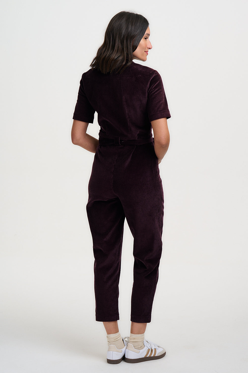 Woman wearing a dark brown jumpsuit on a white background