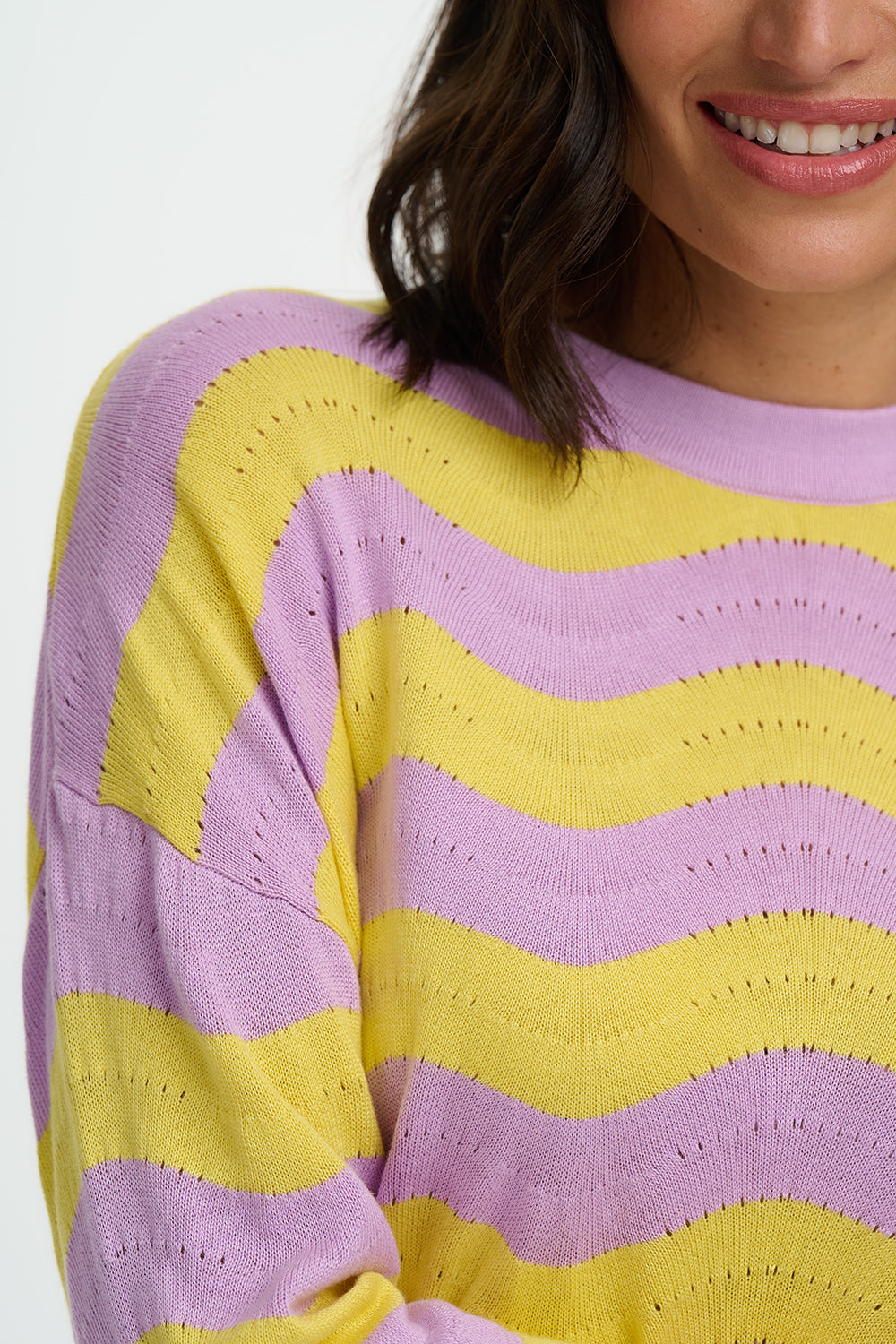 Person wearing a purple and yellow striped sweater on a white background