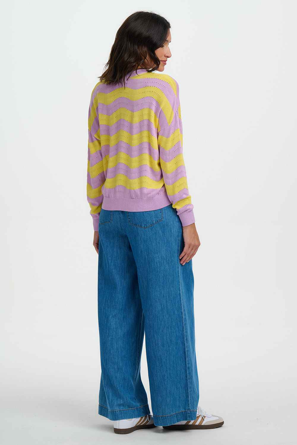 Person wearing a striped sweater and blue jeans on a white background