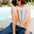 Woman wearing a colorful striped shirt and sunglasses sitting by a pool.