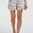 Woman wearing a white top with colorful trim and patterned shorts on a white background