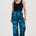 Woman wearing blue patterned pants and a black top on a white background