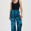 Woman wearing blue patterned pants and a black top on a white background