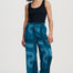 Woman wearing blue patterned pants and a black top on a white background