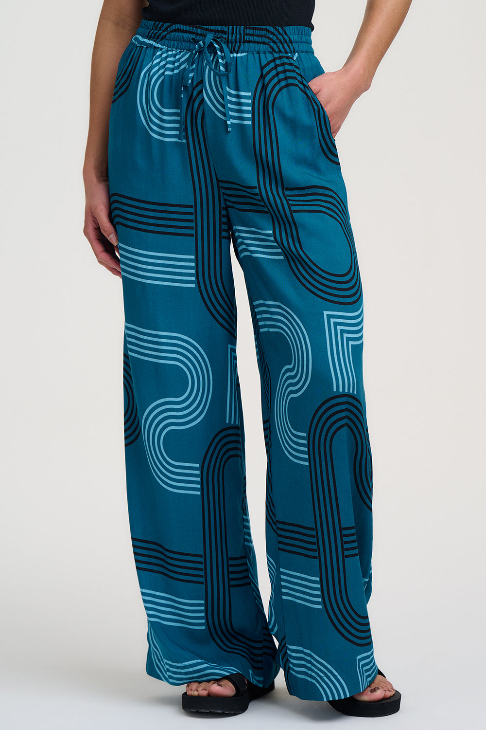 Teal pants with a pattern worn by a person on a white background