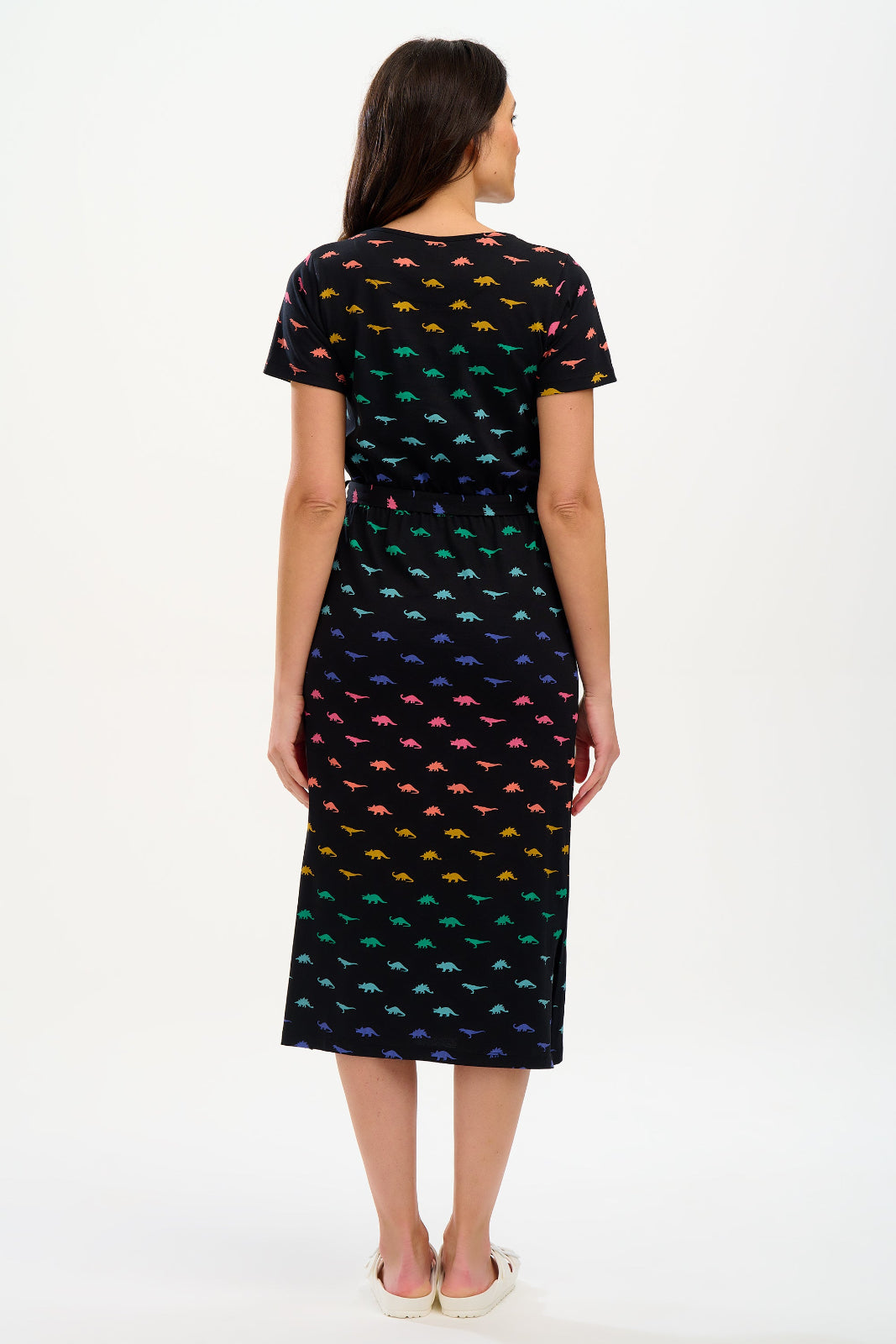 Woman wearing a black dress with colorful dinosaur pattern on a white background