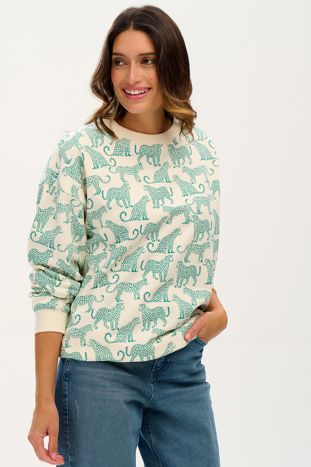 A woman wearing an oversized sweatshirt with a green leopard print on it, paired with blue jeans.
