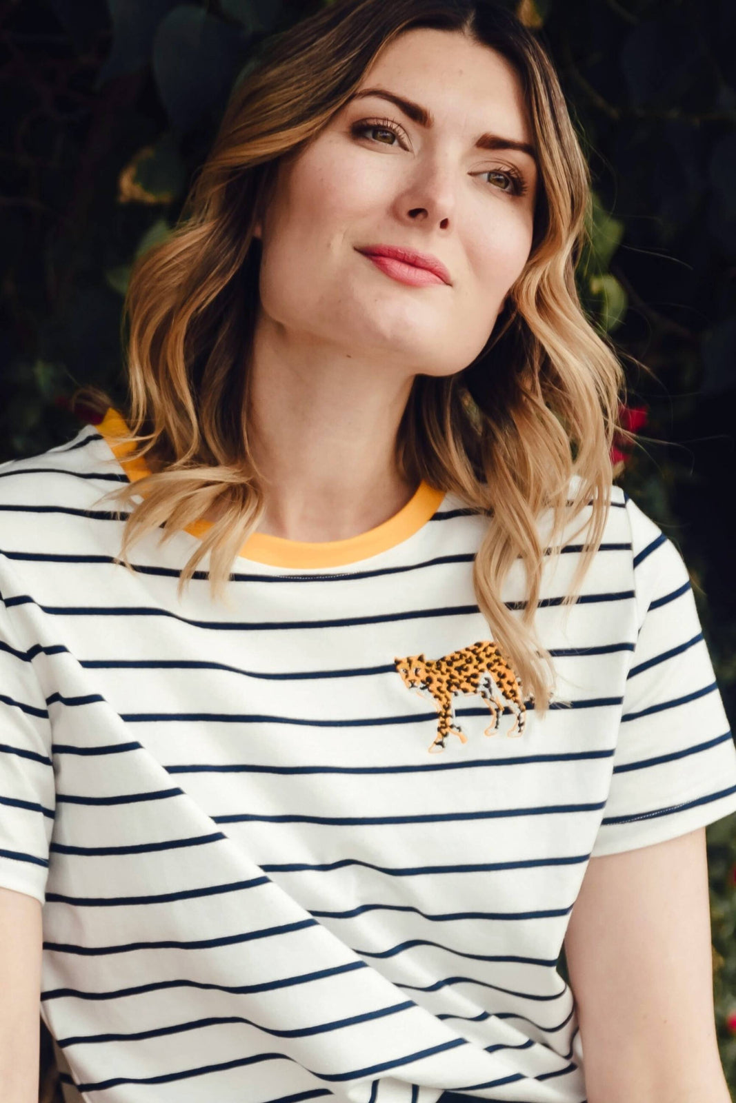A woman wearing an off-white and navy striped t-shirt with a embroidered leopard on the chest.
